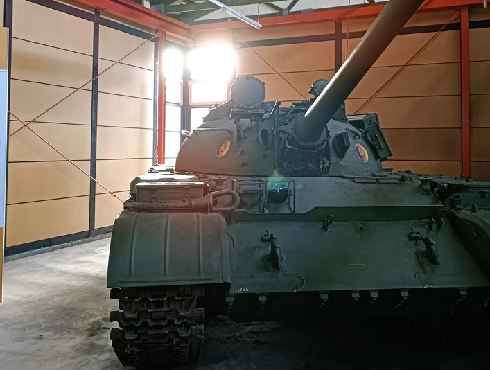 05_DPM_Neue Dauerausstellung_Bereich Kalter Krieg I-min.jpg Ein grüner Panzer aus der Zeit des Kalten Krieges steht in einem Ausstellungsraum neben einer Informationstafel.