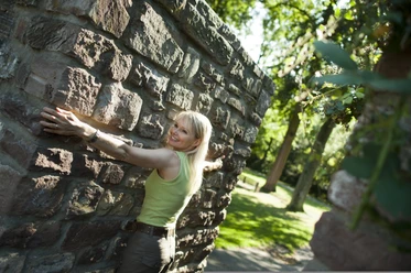 hx-stadtentdecken-andreashub (4).jpg Frau mit ausgebreiteten Armen an der Stadtmauer