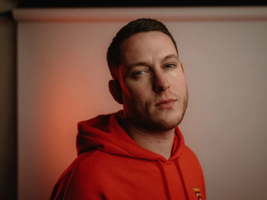 MoTorres_bastisevastos.jpg Ein Mann in einem roten Hoodie blickt mit neutralem Gesichtsausdruck direkt in die Kamera.A man in a red hoodie looks directly into the camera with a neutral expression on his face.Een man met een rode capuchon kijkt recht in de camera met een neutrale uitdrukking op zijn gezicht.En mand i en rød hættetrøje ser direkte ind i kameraet med et neutralt ansigtsudtryk.