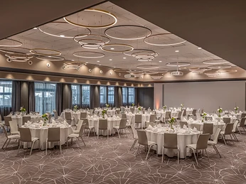 Forum 2 Bankett Moderner, stilvoller Bankettsaal mit runden Tischen, eleganten Stühlen und dekorativer Beleuchtung.</p>Modern, stylish banquet hall with round tables, elegant chairs and decorative lighting.</p> <p