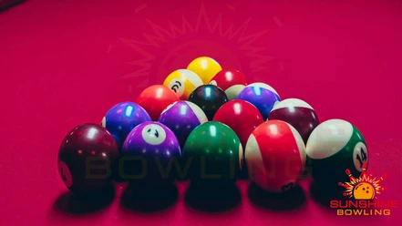 Colorful bowling balls are arranged on a red table, with the Sunshine Bowling logo in the background.