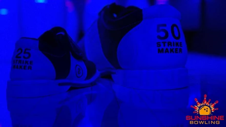 Twee bowlingschoenen in blauw licht, de ene met de inscriptie "25 STRIKE MAKER", de andere "50 STRIKE MAKER", met het logo van Sunshine Bowling ernaast.