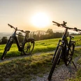 Radfahrer Lügde Zwei Fahrräder stehen auf einem Feldweg bei Sonnenuntergang, umgeben von grünen Wiesen.