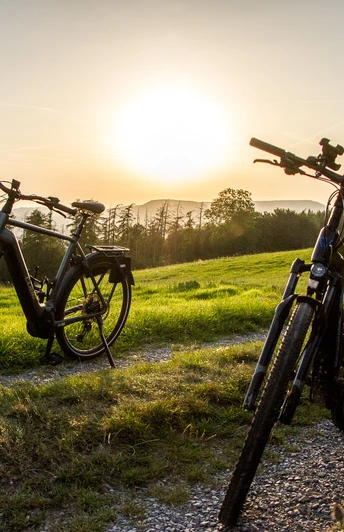 Radfahrer Lügde Zwei Fahrräder stehen auf einem Feldweg bei Sonnenuntergang, umgeben von grünen Wiesen.