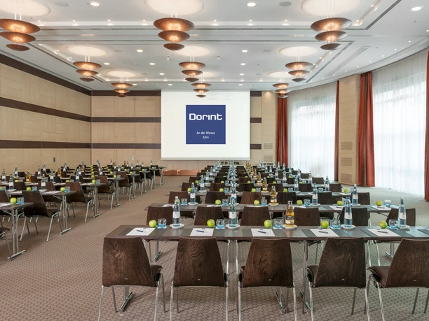Berlin A+B Meeting room with gray carpet, tables, chairs and screen for presentations.