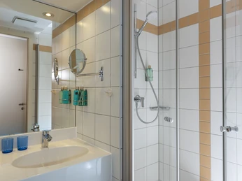 Badezimmer Badezimmer mit Waschbecken, Spiegel, Duschkabine und Seifenspendern an gefliester Wand.Bathroom with washbasin, mirror, shower cubicle and soap dispenser on tiled wall.