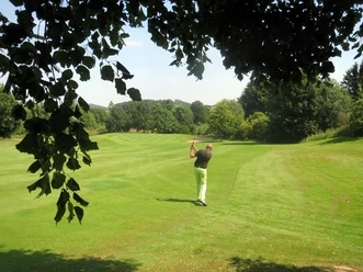 Golfer beim Abschlag auf grünem Fairway des Golfclubs Brilon, umrahmt von Bäumen
