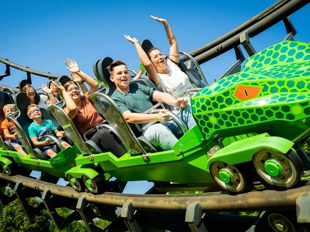 Fort Fun Abenteuerland - Speed Snake Achterbahnzug der Speed Snake mit mehreren winkenden Fahrgästen auf der Strecke.