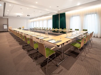Heller Konferenzraum im IntercityHotel Paderborn mit U-förmig aufgestellten Tischen und modernen Stühlen.