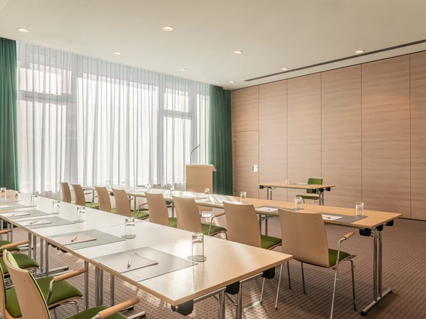 Heller Konferenzraum im IntercityHotel Paderborn mit großen Fenstern, Holzverkleidung und modernen Möbeln.
