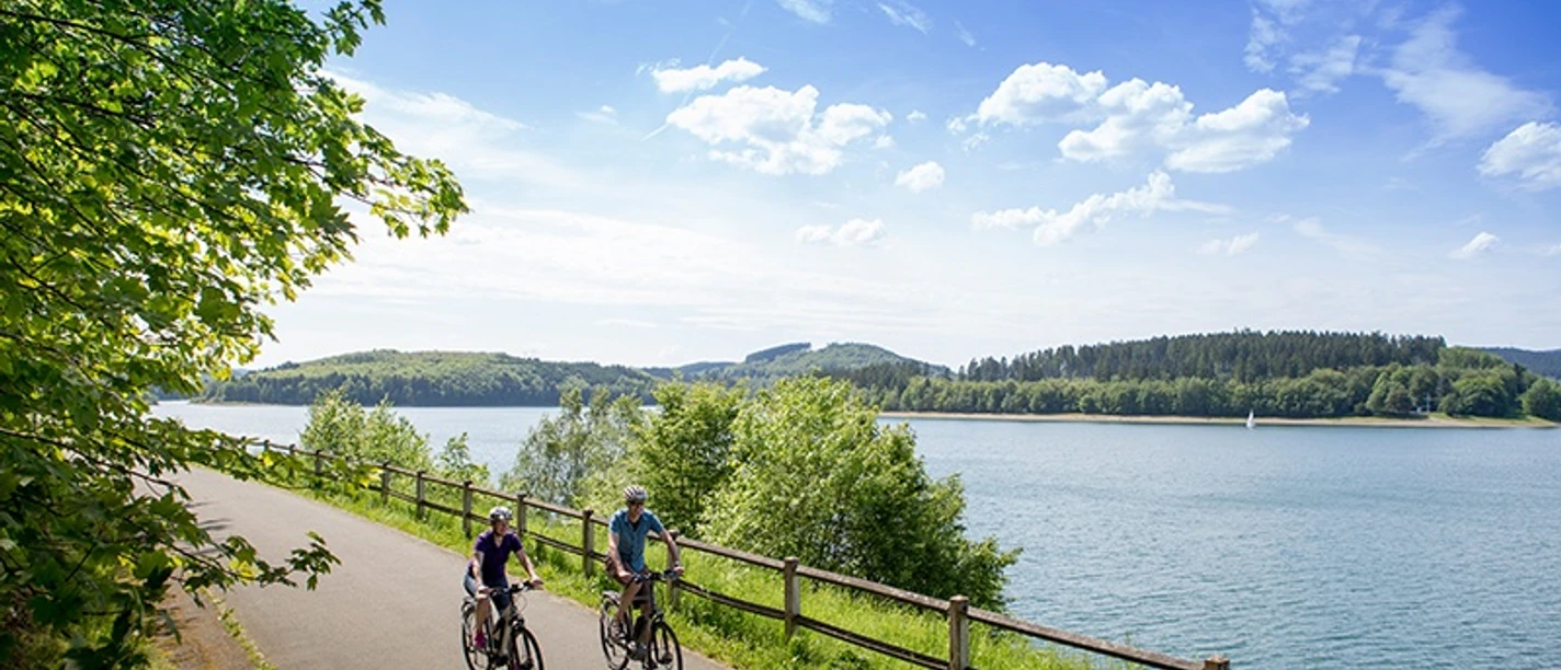 Radfahrer am Biggesee Zwei Radfahrer auf dem Uferweg am Biggesee, mit Wald, Wasser und weitem Himmel