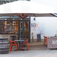 Restaurant Kö13 mit Außenterrasse, modernen orange-grauen Möbeln und großen Sonnenschirm.