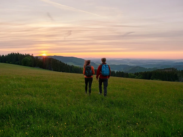 Auf dem Sauerland-Seelenort Krutenberg Zwei Wanderer am Krutenberg im Sonnenaugang