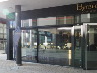 Glasfassade eines modernen Restaurants mit dem Namen "Bobberts", schlichte Innenansicht sichtbar.