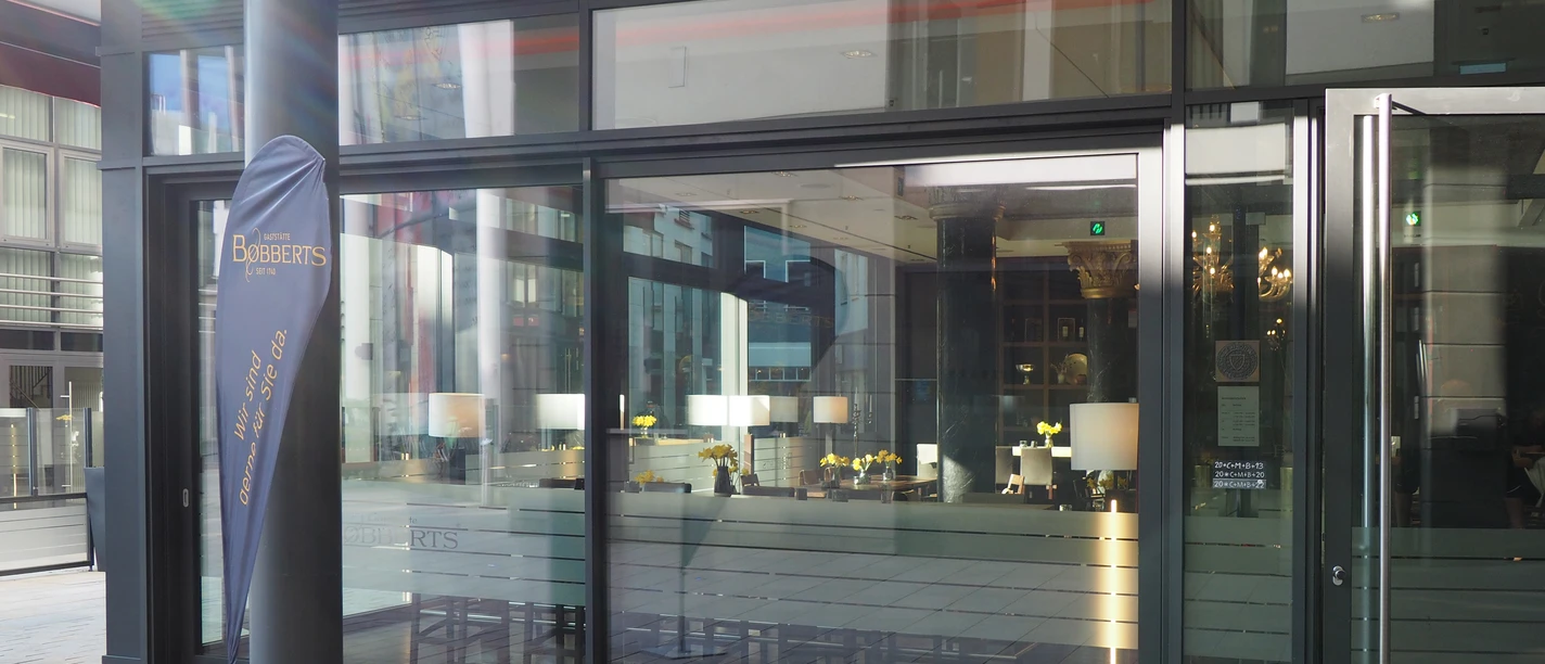 Glasfassade eines modernen Restaurants mit dem Namen "Bobberts", schlichte Innenansicht sichtbar.