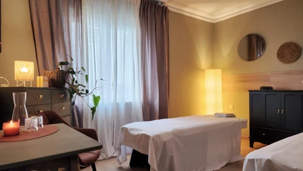 Behandlungsraum von Scaria Wellness mit Massageliege, Kerzenlicht und warmen Lampen