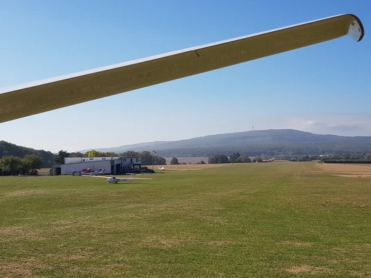 Flugplatz in Ober-Mörlen Flugplatz in Ober-Mörlen mit mehreren Segelfliegern am Boden. Im Hintergrund ist der Große Feldberg zu sehen.
