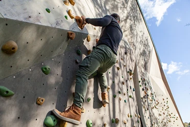 Die Boulderwand am Taunus-Informationszentrum ist jederzeit öffentlich zugänglich Ein Mann klettert an der Boulderwand im Freien nach oben