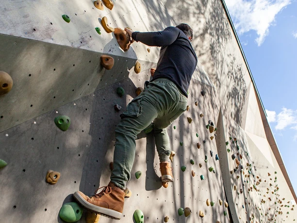Die Boulderwand am Taunus-Informationszentrum ist jederzeit öffentlich zugänglich Ein Mann klettert an der Boulderwand im Freien nach oben