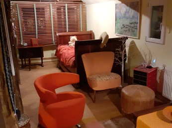 Ein Wohnzimmer mit Holzboden, roten Akzenten, Seilzugsessel, Kissen und dekorativen Kunstwerken.