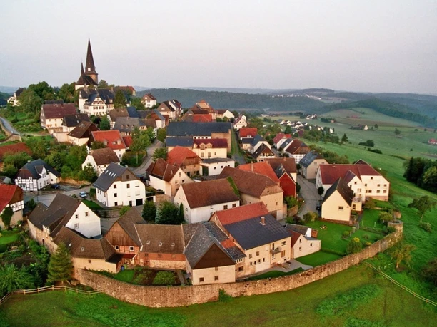 Blick auf Kallenhardt mit Kirche, Fachwerkhäusern und grüner Hügellandschaft