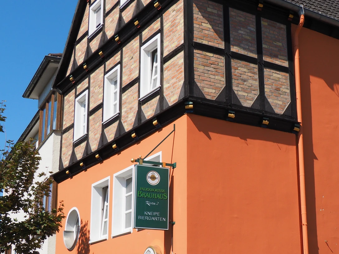 Historisches Fachwerkgebäude mit orangefarbener Fassade und Brauereischild an der Hauswand.