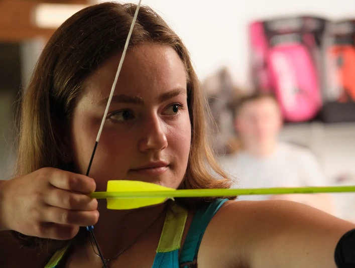 Konzentration aufs Ziel Nahaufnahme einer Bogenschützin, die den Bogen spannt