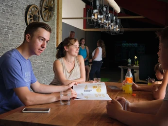 Gemütlich sitzen Eine Gruppe junger Menschen sitzt an einem Tisch in einem Restaurant. Im Hintergrund steht eine weitere Gruppe