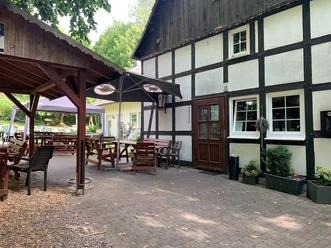 Fachwerkfassade des Gasthofs Zur Bohnenburg mit Biergarten und Sonnenschirmen in Suttrop