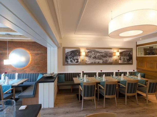 Restaurant Hotel Holländer Hof Grevenstein Restaurantinnenraum mit gedeckten Tischen, Sitzbänken und historischen Schwarz-Weiß-Fotografien.