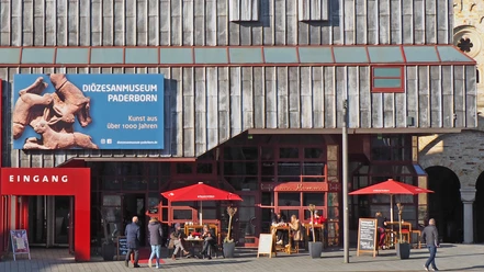 Café Ostermann am Museum mit roten Sonnenschirmen und Außenbereich neben Diozesanmuseum.