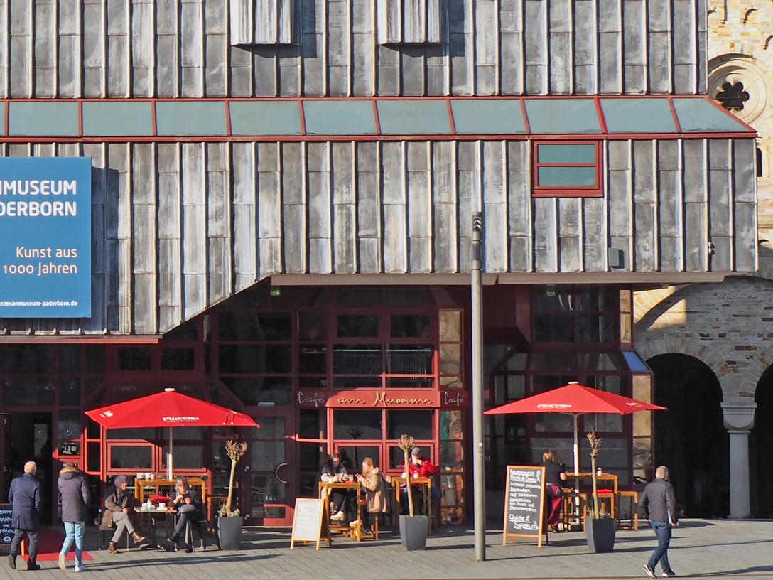 Café Ostermann am Museum mit roten Sonnenschirmen und Außenbereich neben Diozesanmuseum.