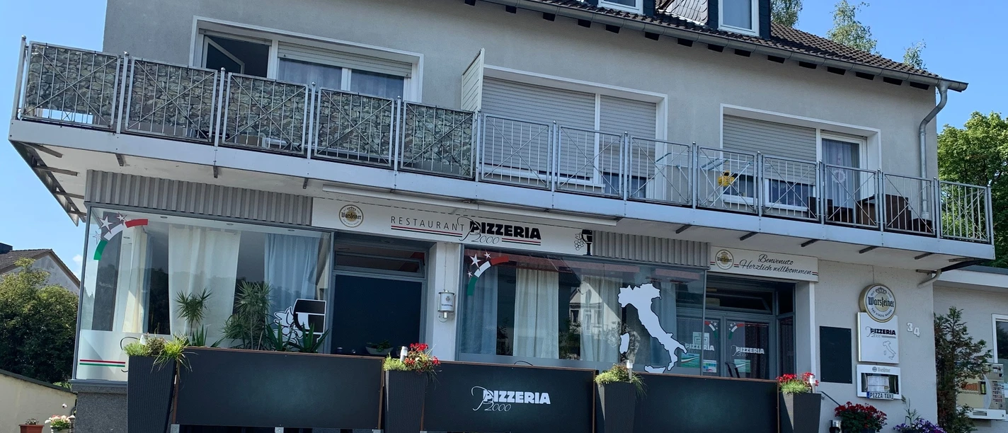 Pizzeria 2000, Belecke Außenansicht der Pizzeria 2000 in Belecke mit Terrasse und Balkon bei Sonnenschein