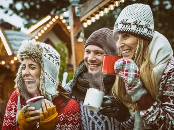 Weihnachten_3.jpeg Drei lachende Personen in Winterkleidung genießen heiße Getränke auf einem festlichen Weihnachtsmarkt.</p>Three smiling people in winter clothes enjoying hot drinks at a festive Christmas market.</p> <p