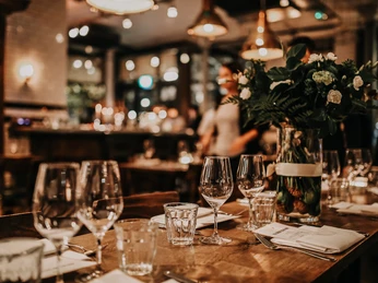 Weihnachten_2.jpeg <p>Elegantes Restaurant mit gedecktem Tisch, Weingläsern und Blumen im sanften Kerzenlicht.</p>