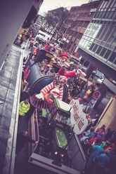 Karneval_1.jpg A colorful float with a giant clown and cyclists during a carnival parade.