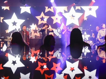 4_Events.jpg Live-Band spielt auf Bühne; Leuchtsterne im Hintergrund; Publikum in vorderem Bereich.Live band plays on stage; illuminated stars in the background; audience in the front area.