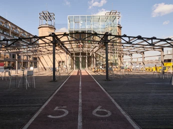 Museumsterrasse (21).jpg Moderner Pavillon mit Glasfassade, flankiert von zwei Türmen und umgeben von Metallstruktur.</p>Modern pavilion with glass façade, flanked by two towers and surrounded by metal structure.</p> <p