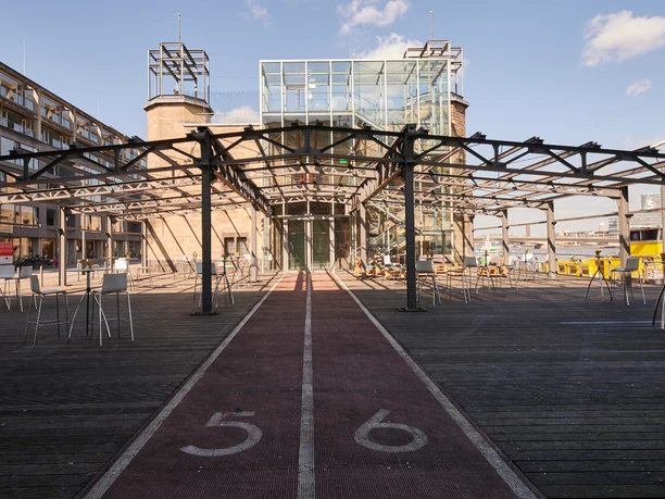 Museumsterrasse (21).jpg Moderner Pavillon mit Glasfassade, flankiert von zwei Türmen und umgeben von Metallstruktur.</p>