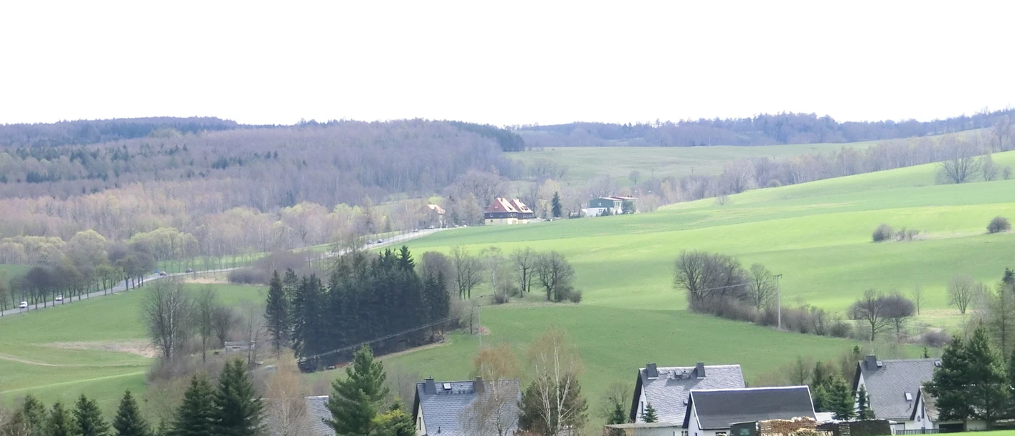 View of a wide, hilly landscape near Hellendorf, surrounded by fields and scattered houses.