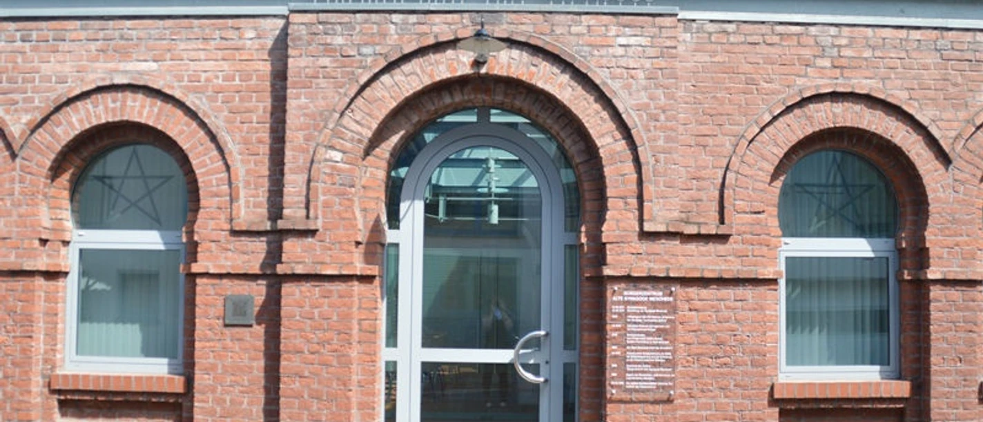 Bürgerzentrum Alte Synagoge Meschede Backsteinfassade einer ehemaligen Synagoge mit rundbogigen Fenstern und Metalltür.