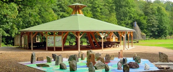 Steine im Geologischen Garten Giershagen vor einem offenen Holzpavillon im Grünen