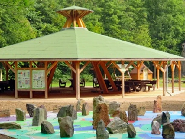 Steine im Geologischen Garten Giershagen vor einem offenen Holzpavillon im Grünen