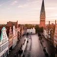 Platz am Sande in Lüneburg Platz Am Sande mit historischen Giebelhäusern und der St. Johanniskirche im Sonnenlicht.