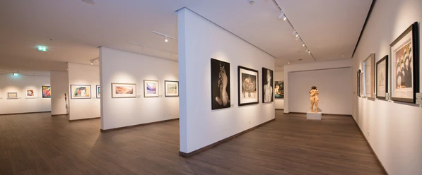 Kunstsammlung Henning J. Claassen Moderner Ausstellungsraum in der Kunstsammlung Henning J. Claassen mit gerahmten Kunstwerken an weißen Wänden und dunklem Holzboden.