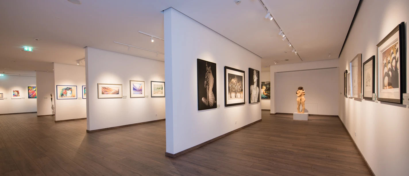 Kunstsammlung Henning J. Claassen Moderner Ausstellungsraum in der Kunstsammlung Henning J. Claassen mit gerahmten Kunstwerken an weißen Wänden und dunklem Holzboden.