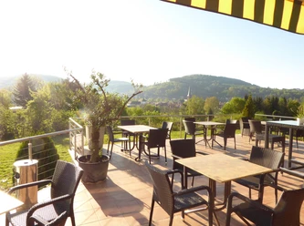 Terrasse Hotel-Restaurant Sonnenhof Panoramablick von der Hotel-Restaurant Terrasse auf grüne Hügel mit leeren Tischen im Sonnenlicht.