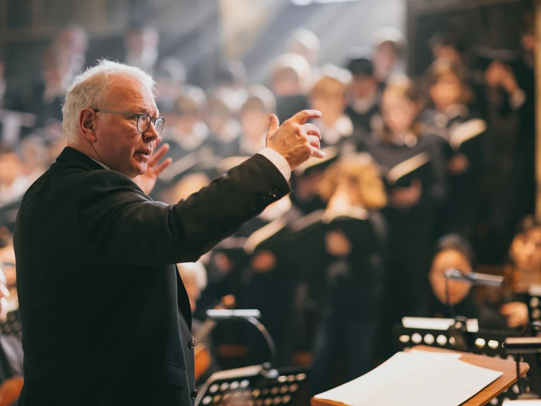 Ein Chorleiter dirigiert mit den Domchor bei einem festlichen Konzert.