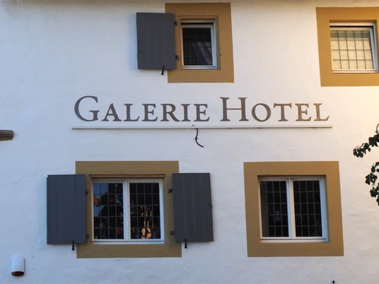 Weißes Gebäude im traditionellen Stil mit Holzfensterläden und einem Schild mit der Aufschrift "Hotel".