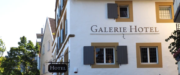La Petite Galerie Weißes Gebäude im traditionellen Stil mit Holzfensterläden und einem Schild mit der Aufschrift "Hotel".